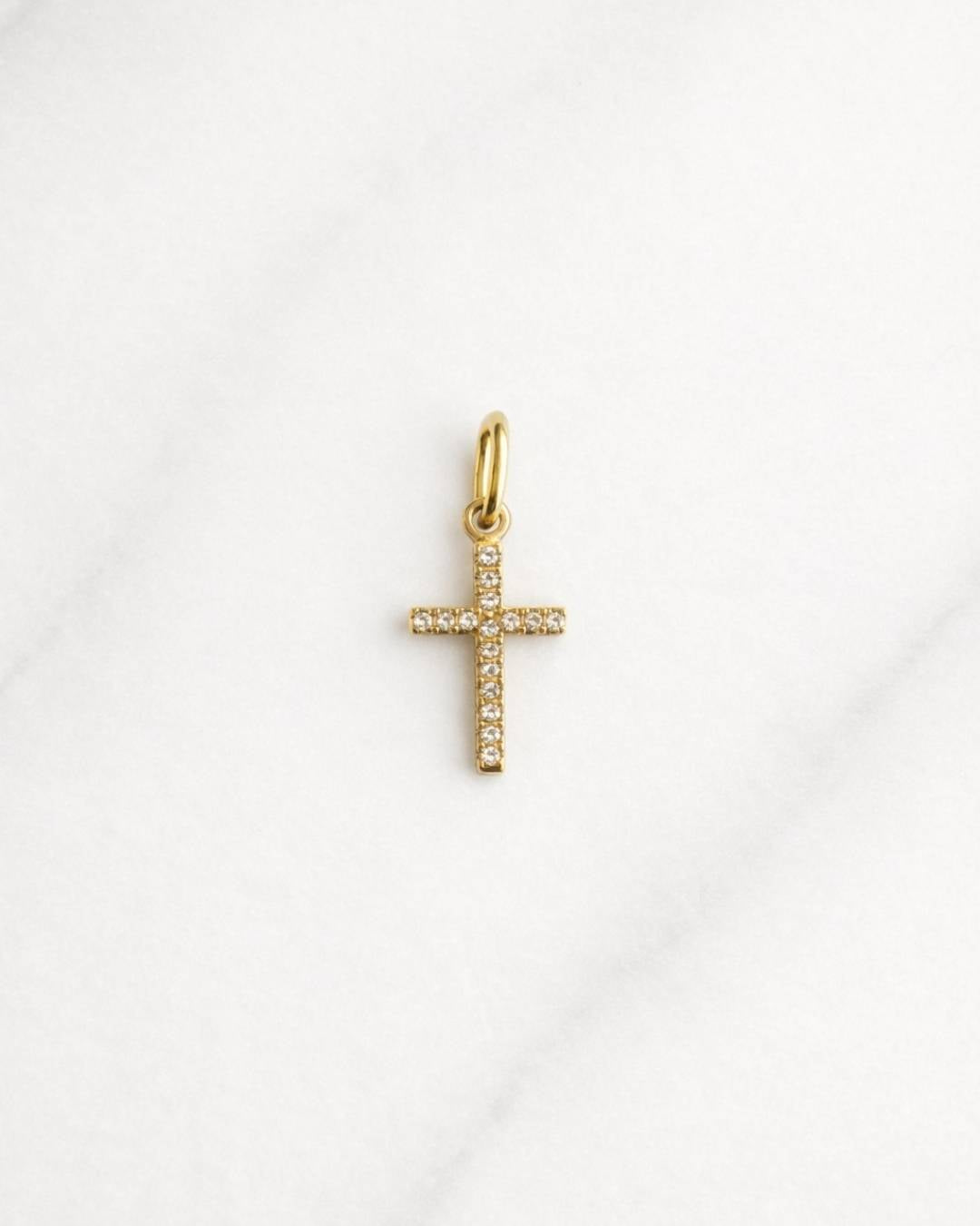 Ravenna CHARM goldener Kreuzanhänger mit Zirkonia auf hellem Marmorhintergrund.