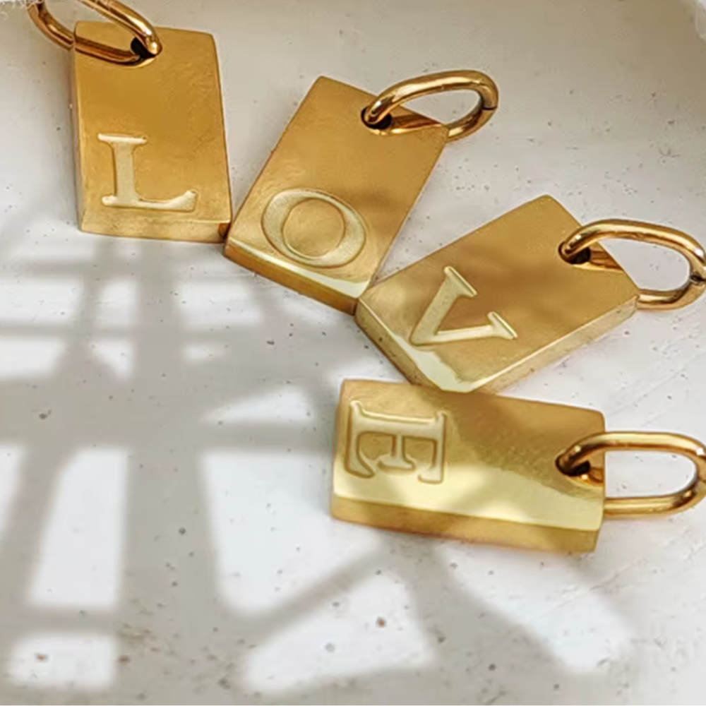 Alphabet Buchstabenanhänger Gold aus Edelstahl, stilvoll präsentiert auf Stoffhintergrund, Damenschmuck