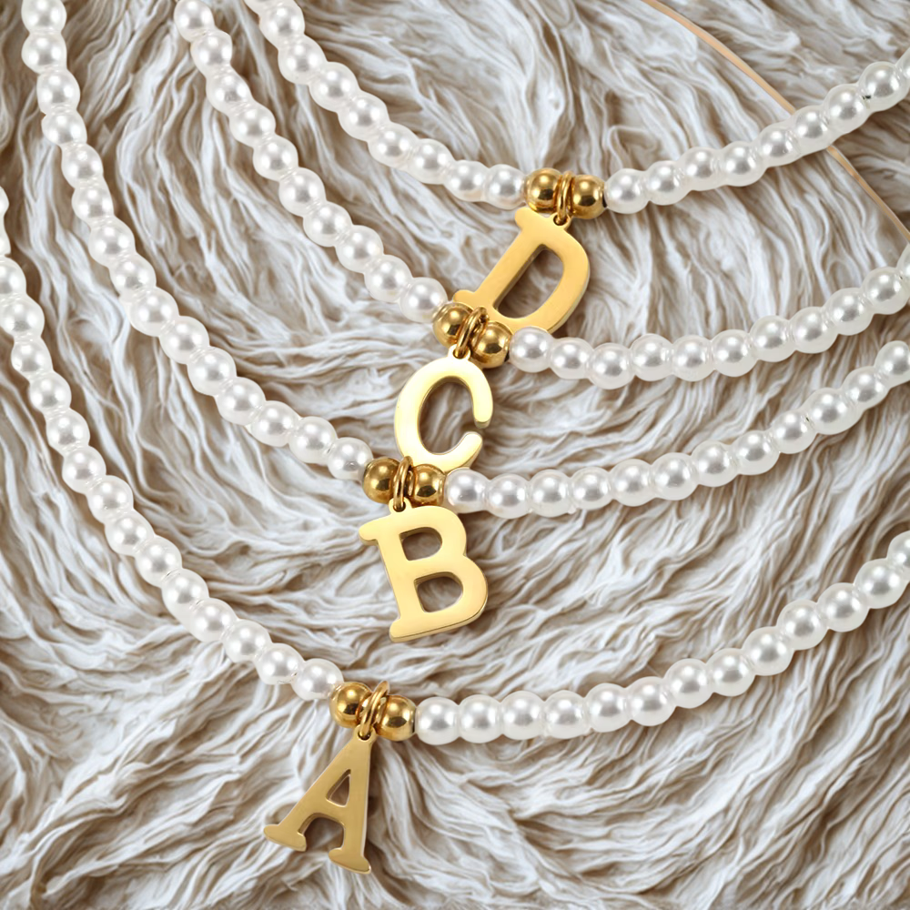 Personalisierte Alphabet Perlenkette aus Edelstahl in Gold mit Buchstabenanhänger, modernes Schmuckdetail
