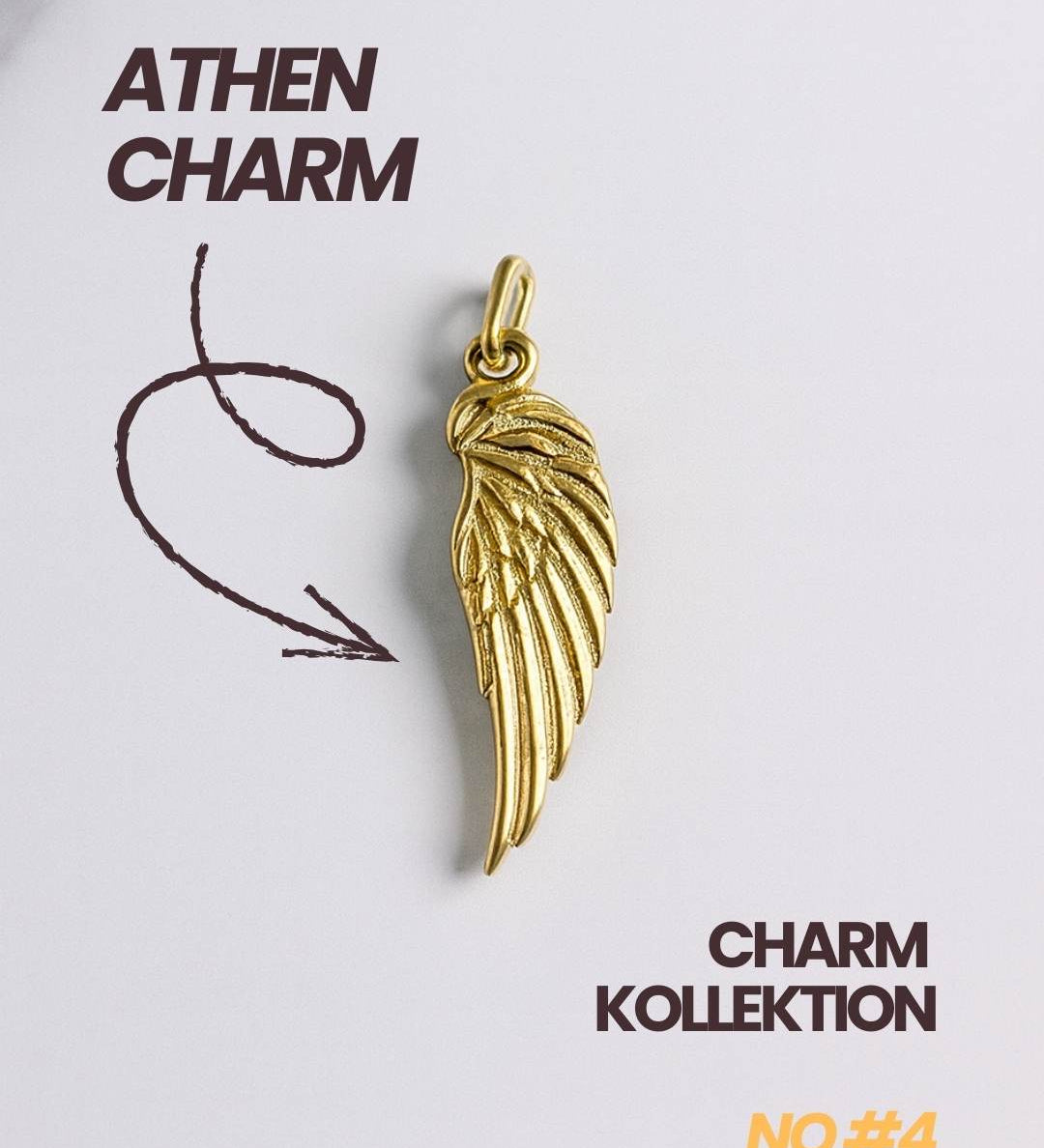 Detailaufnahme eines vergoldeten Flügel Charms der Athen Kollektion auf weißem Hintergrund