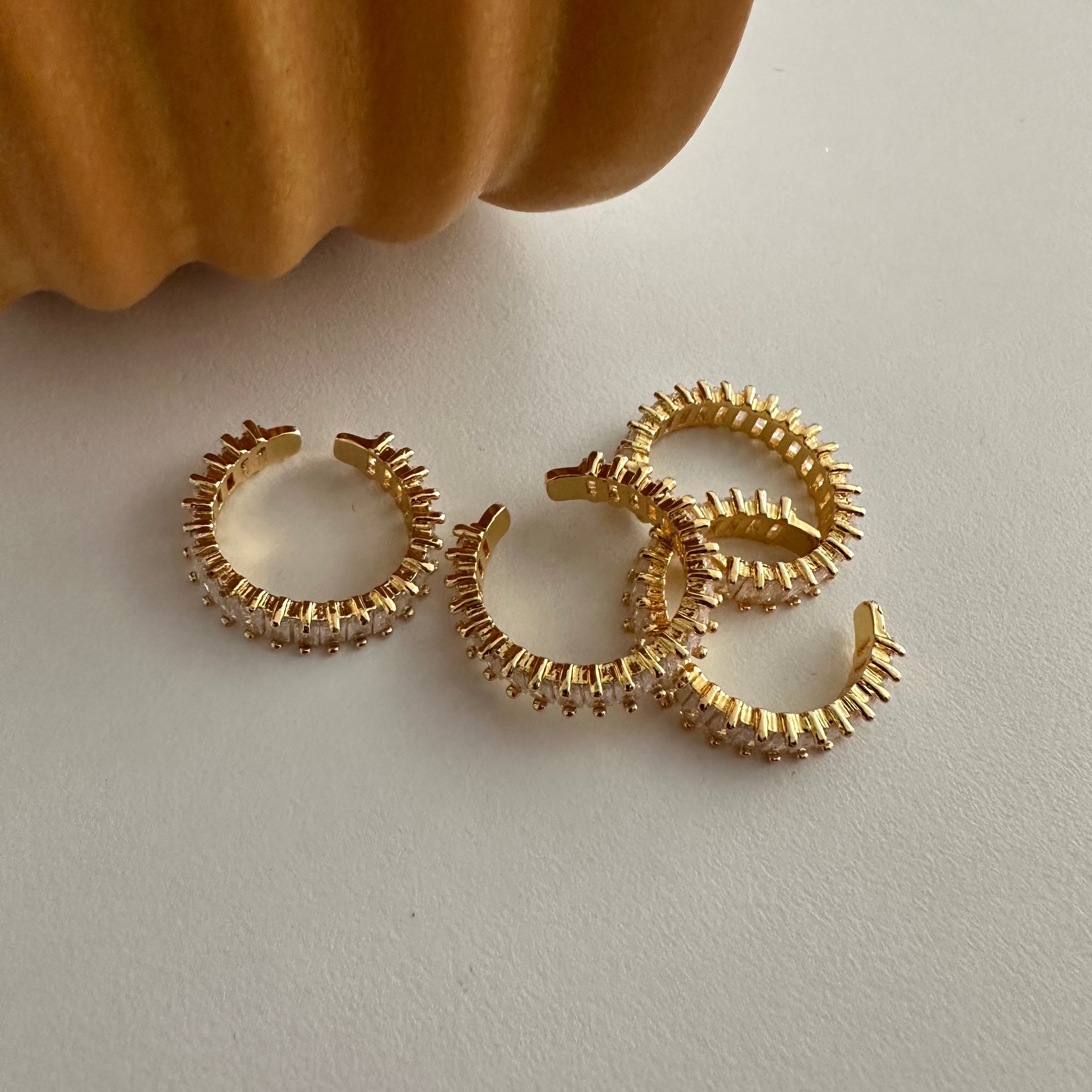 Mehrere goldene Baguette Ringe liegen dekorativ nebeneinander auf einem hellen Untergrund.