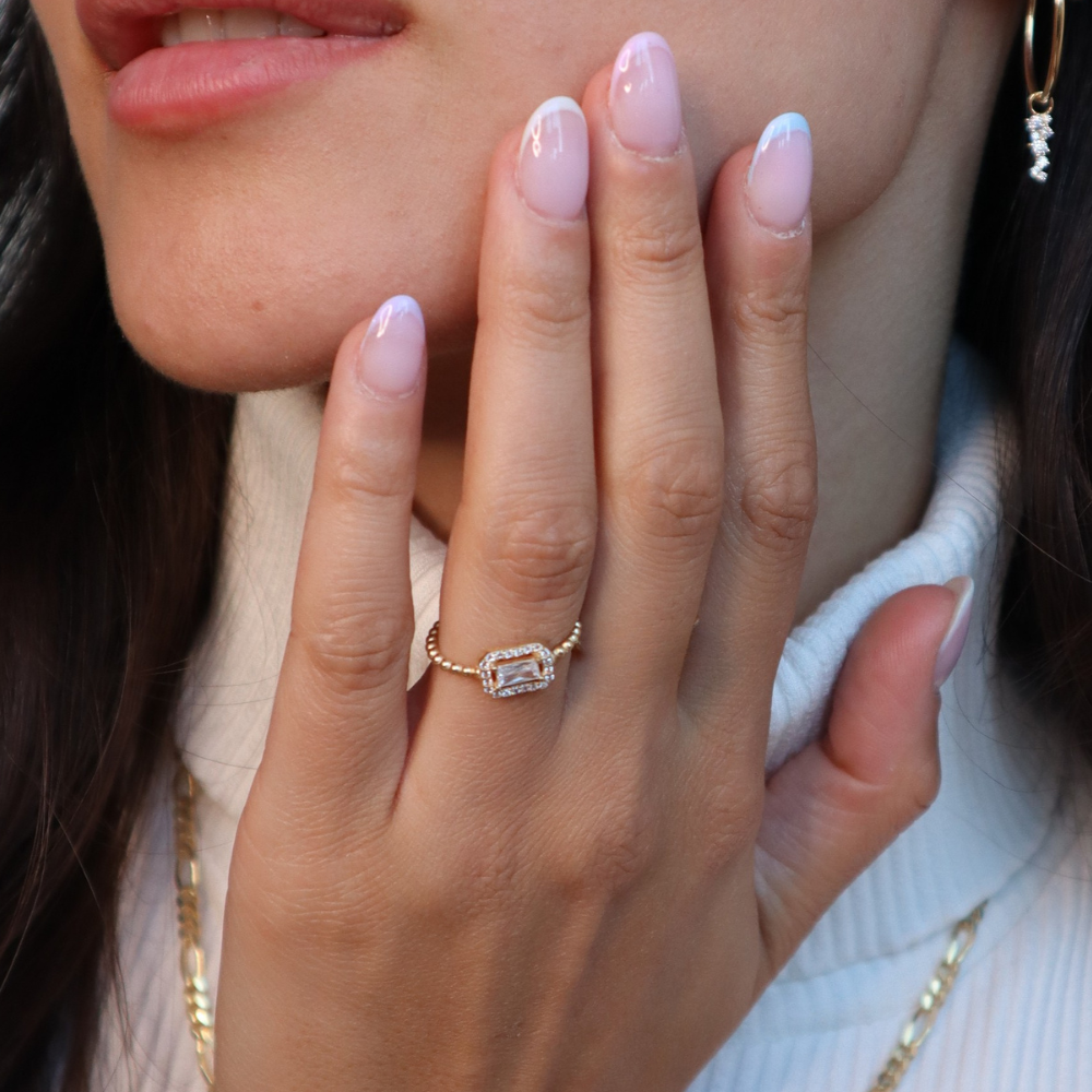Baguette White Ring in Gold am Finger getragen, Zirkonia mit Halo, eleganter Alltagsring.