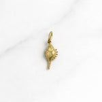 Goldener Bali Charm in Muschel-Design, kleiner Anhänger aus Edelstahl mit 18K Vergoldung auf hellem Hintergrund.