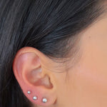 Silberne Balls L Stud Kugel-Ohrstecker aus 925 Sterling Silber in drei Größen am Ohr einer Frau getragen.