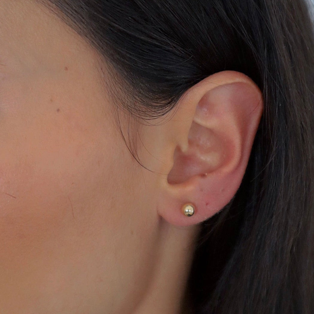 Goldene Balls L Stud Kugel-Ohrstecker aus 925 Sterling Silber dezent am Ohr einer Frau getragen.