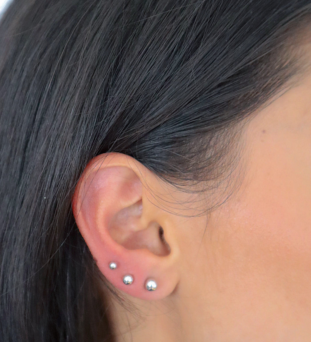 Balls S Stud Ohrstecker Silber im Ohr getragen, filigraner Look mit mehreren Piercings.