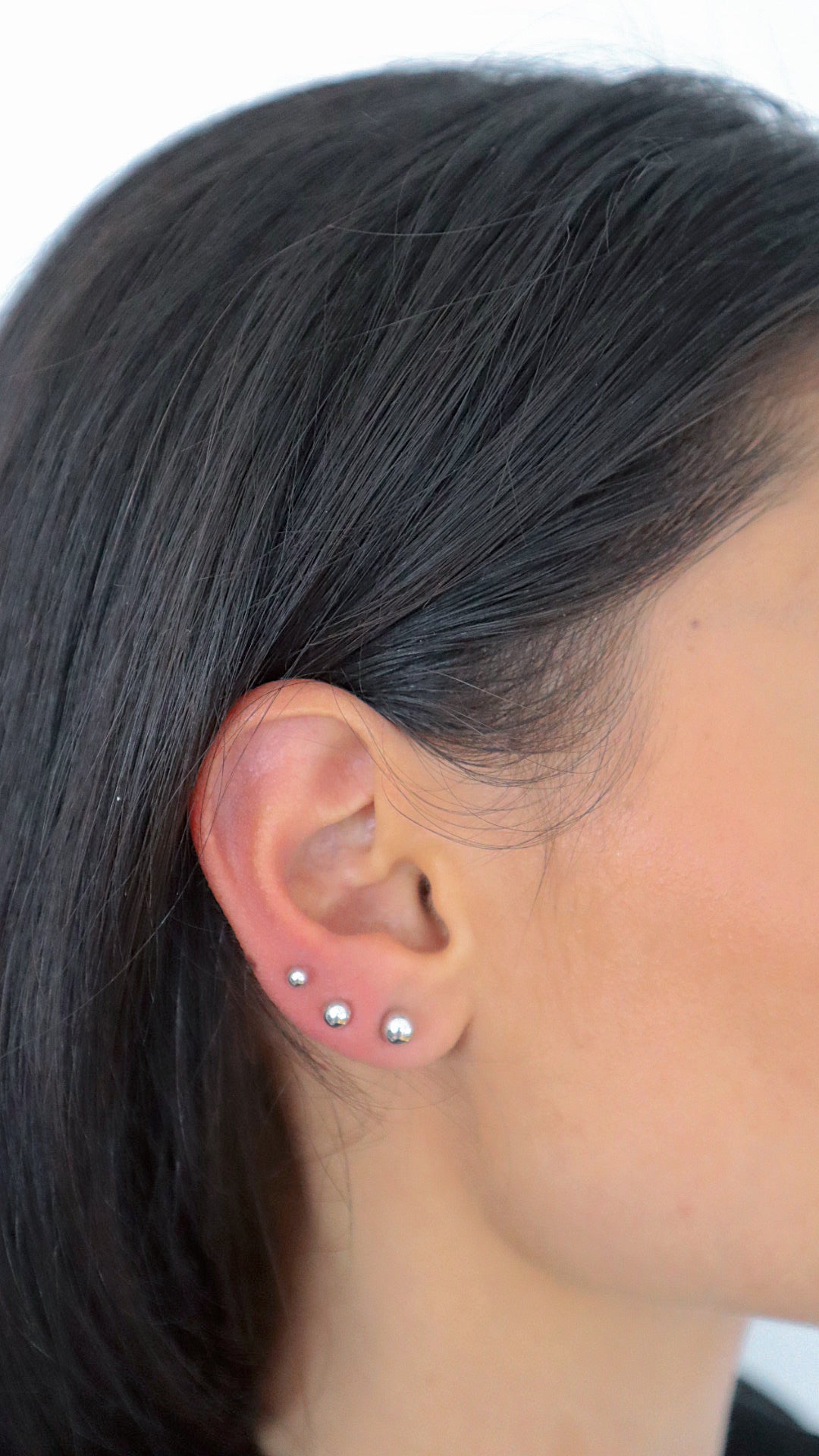 Balls S Stud Ohrstecker Silber im Ohr getragen, filigraner Look mit mehreren Piercings.