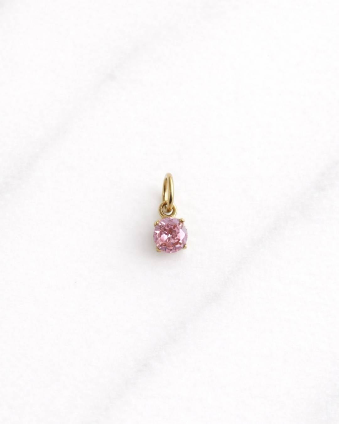 Goldener Bellagio CHARM mit pinkem Stein auf hellem Hintergrund, eleganter Schmuck.