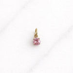 Goldener Bellagio CHARM mit pinkem Stein auf hellem Hintergrund, eleganter Schmuck.