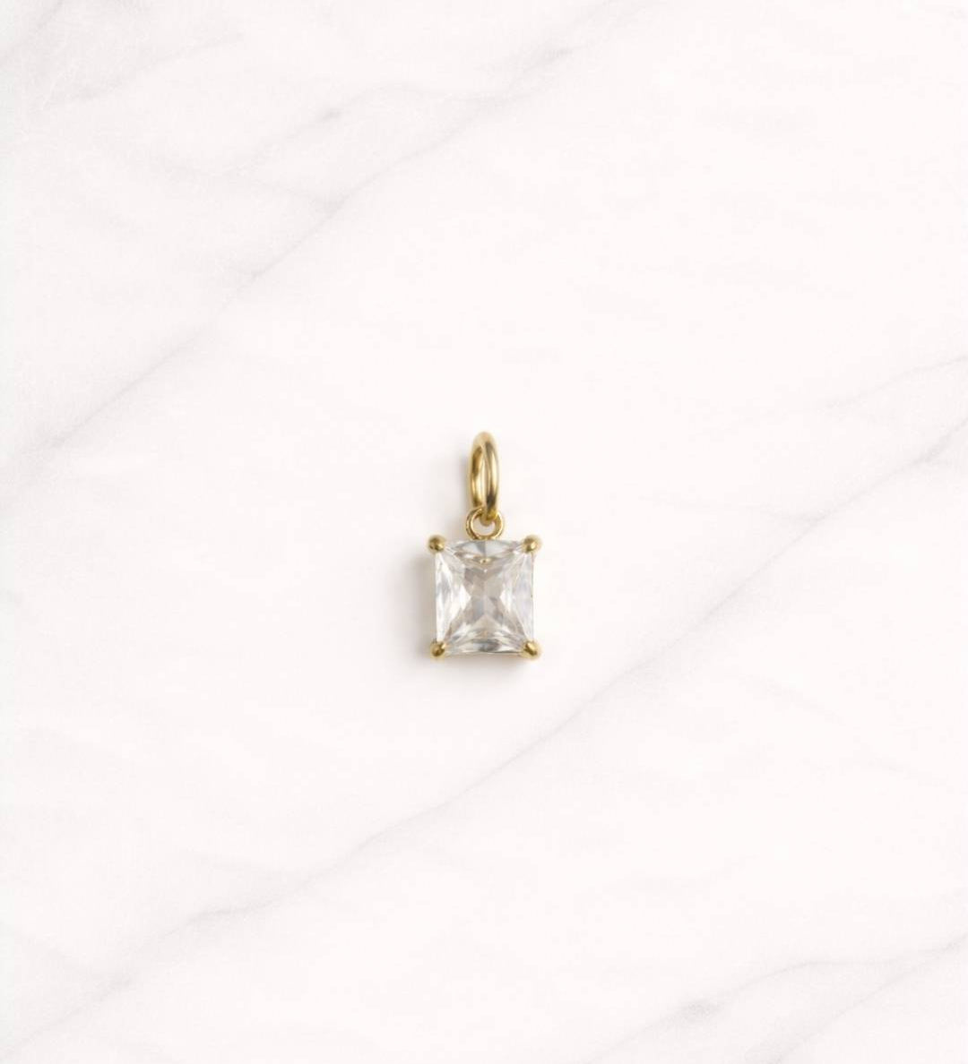 Belmont CHARM in Gold mit klarem rechteckigem Schmuckstein auf hellem Hintergrund.