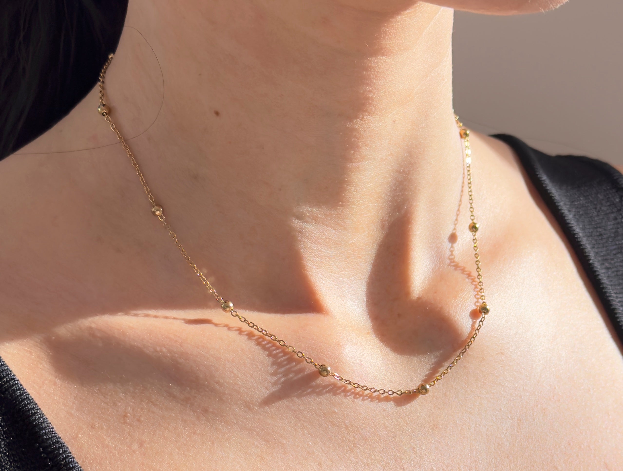 Nahaufnahme Bubble Chain Goldkette mit kleinen Kugeln, 18K vergoldeter Edelstahl an Frauenhals, zarter Damenschmuck.