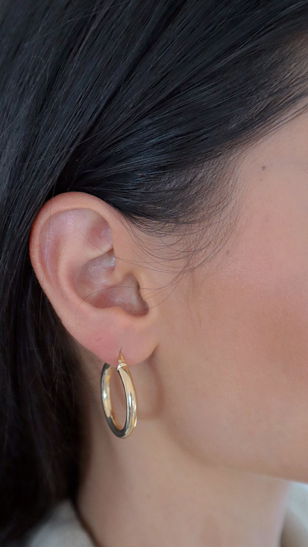 Bump M Creolen in Gold am Ohr einer Frau, mittelgroße elegante Hoops für Alltag und Abendlook.