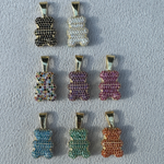 Acht Bärchen Anhänger in Gold: Schwarz, Weiss, Lila, Pink, Multicolor, Blau, Grün, Orange.