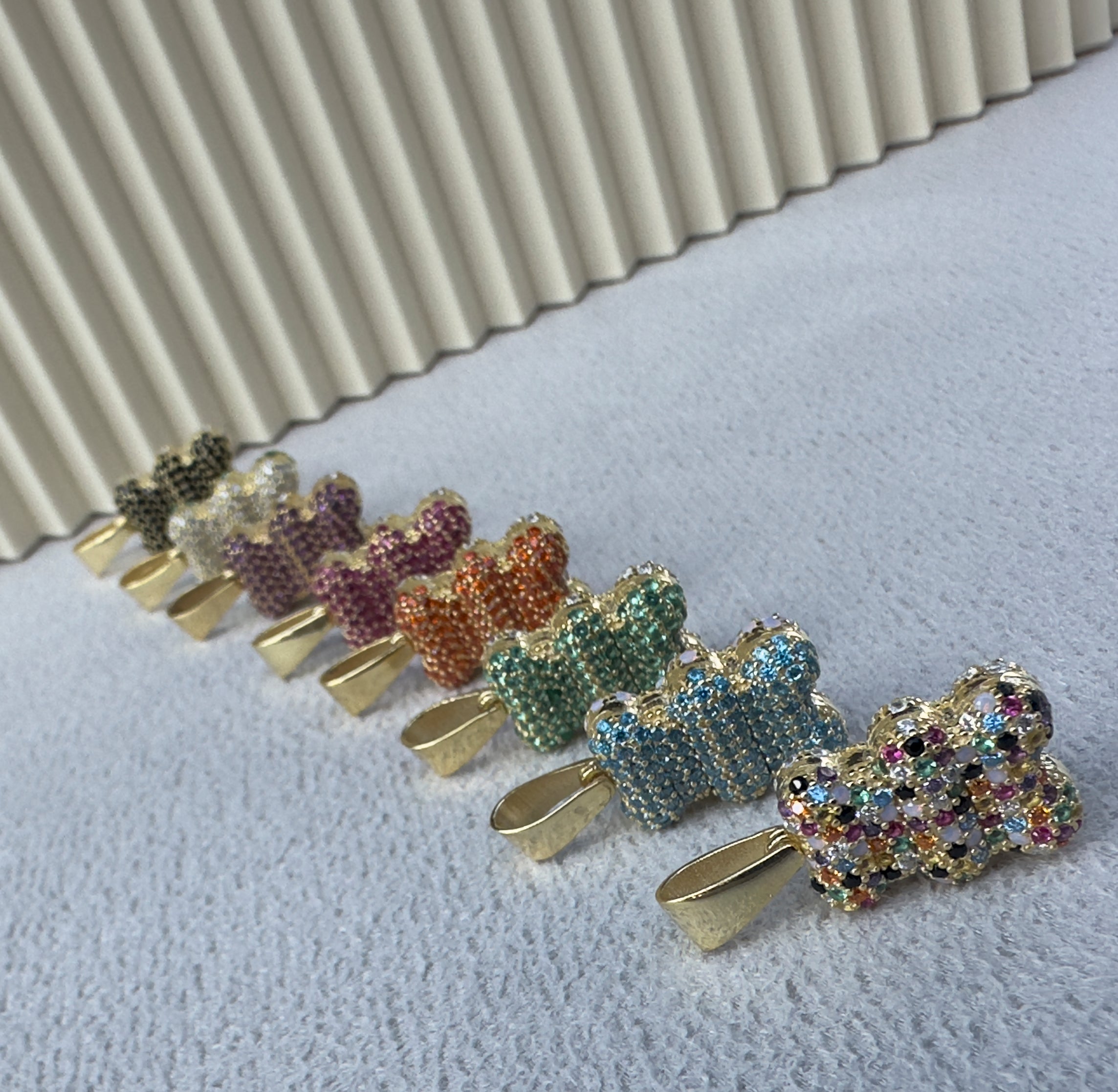 Reihe goldener Bärchen Anhänger mit bunten Zirkonia, funkelnde Nahaufnahme.