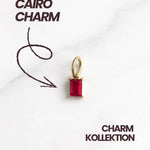 Cairo Charm aus der Charm Kollektion No. 17, goldfarbener Anhänger mit rotem Stein.