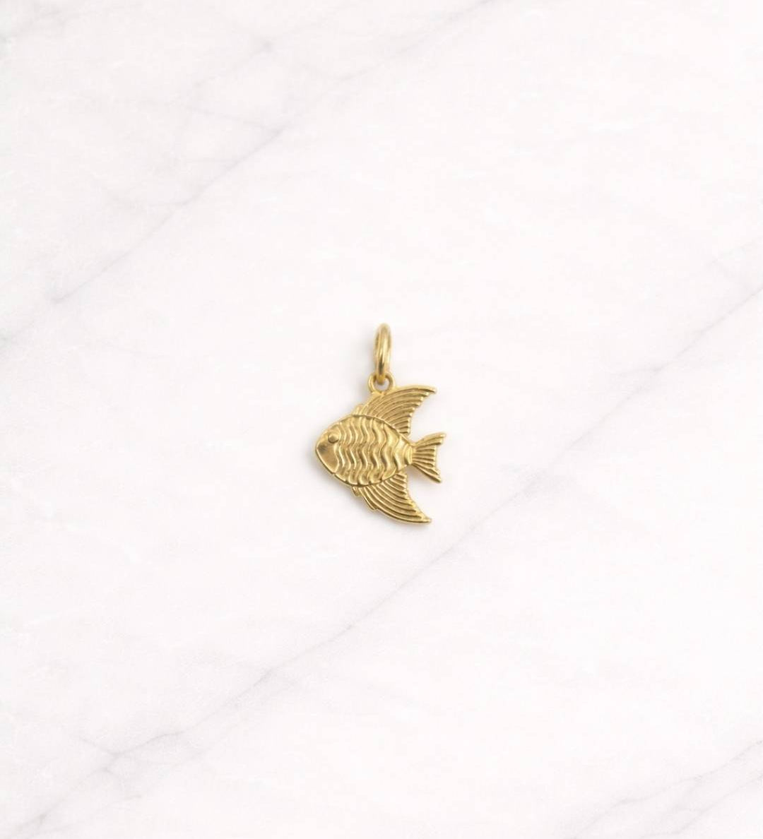 Cannes CHARM in Gold mit elegantem Fischmotiv auf hellem Hintergrund.