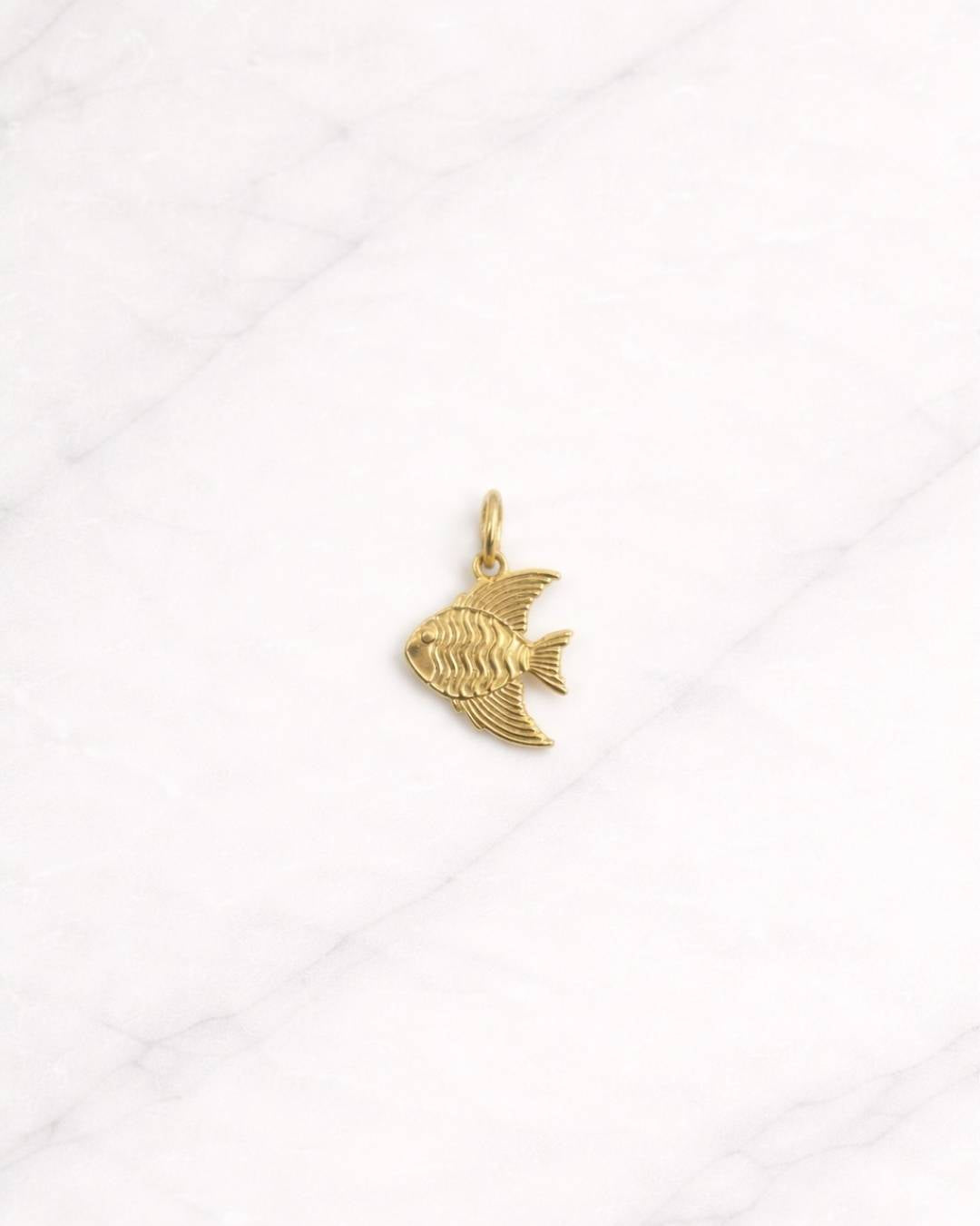 Cannes CHARM in Gold mit elegantem Fischmotiv auf hellem Hintergrund.