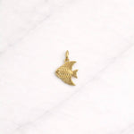 Cannes CHARM in Gold mit elegantem Fischmotiv auf hellem Hintergrund.
