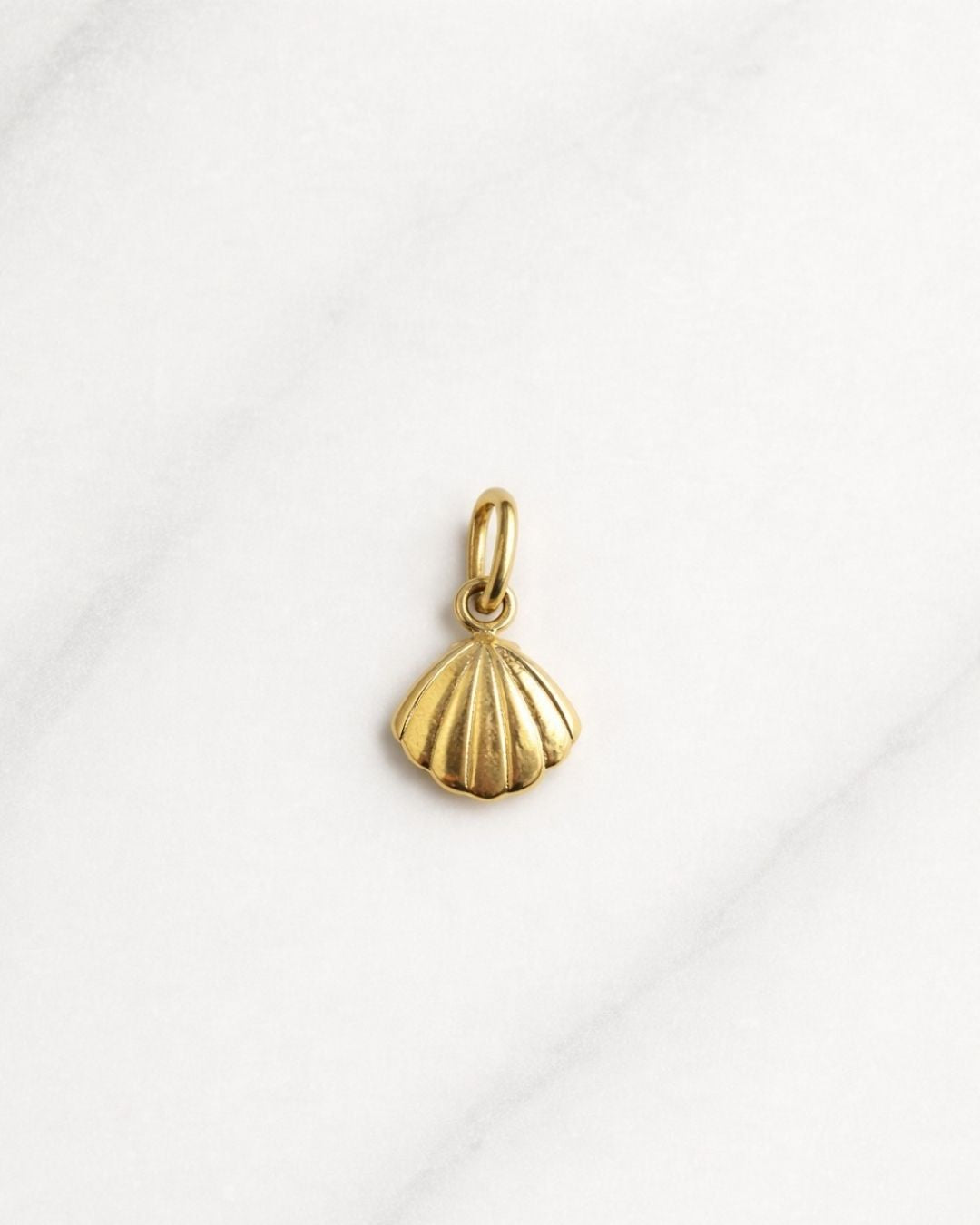 Capri Charm in Gold – kleiner Muschel-Anhänger auf hellem Hintergrund.