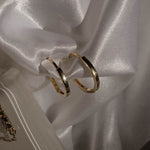 Flatlay: Classy Hoops L Creolen Gold auf Satinstoff – 925 Silber, 14K vergoldet, zeitlos minimalistisch.