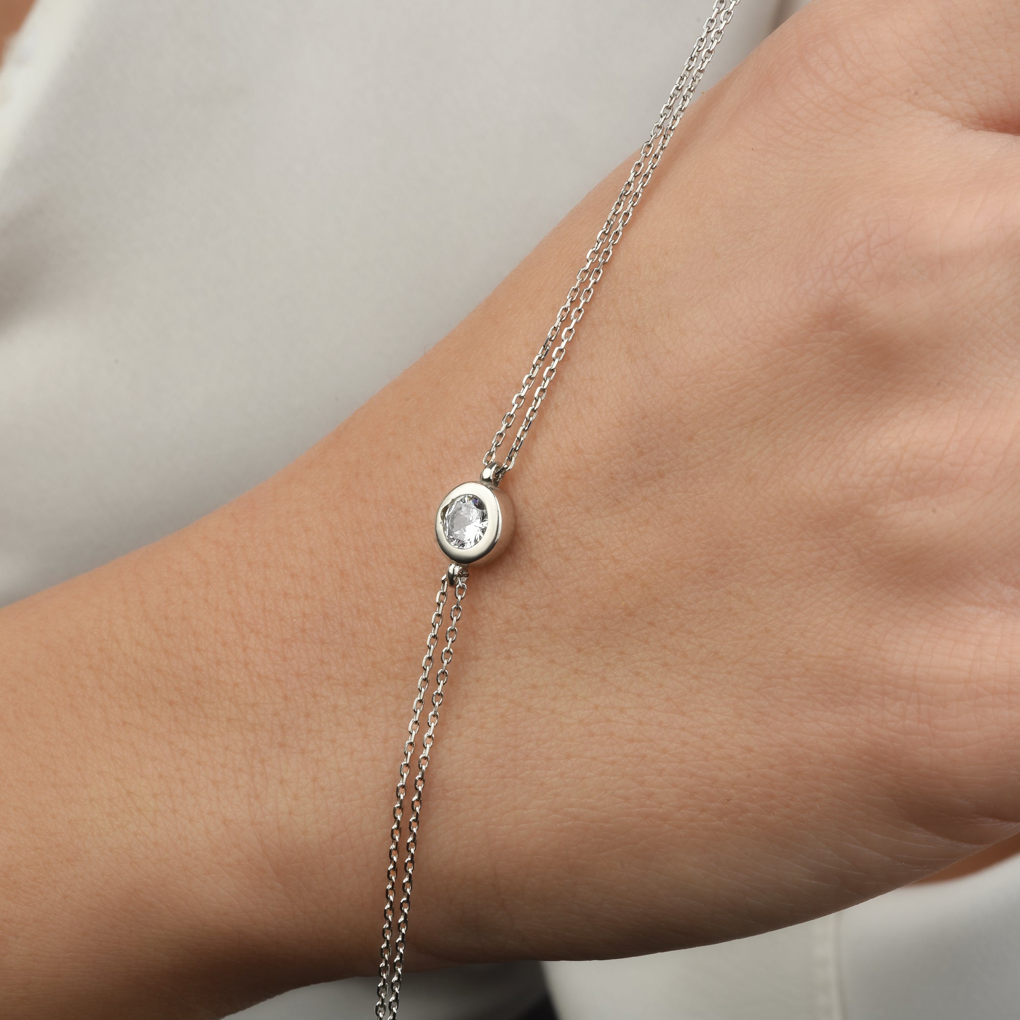 Solitaire Armband Silber am Handgelenk, feine Doppel-Kette mit rundem Zirkonia Stein.