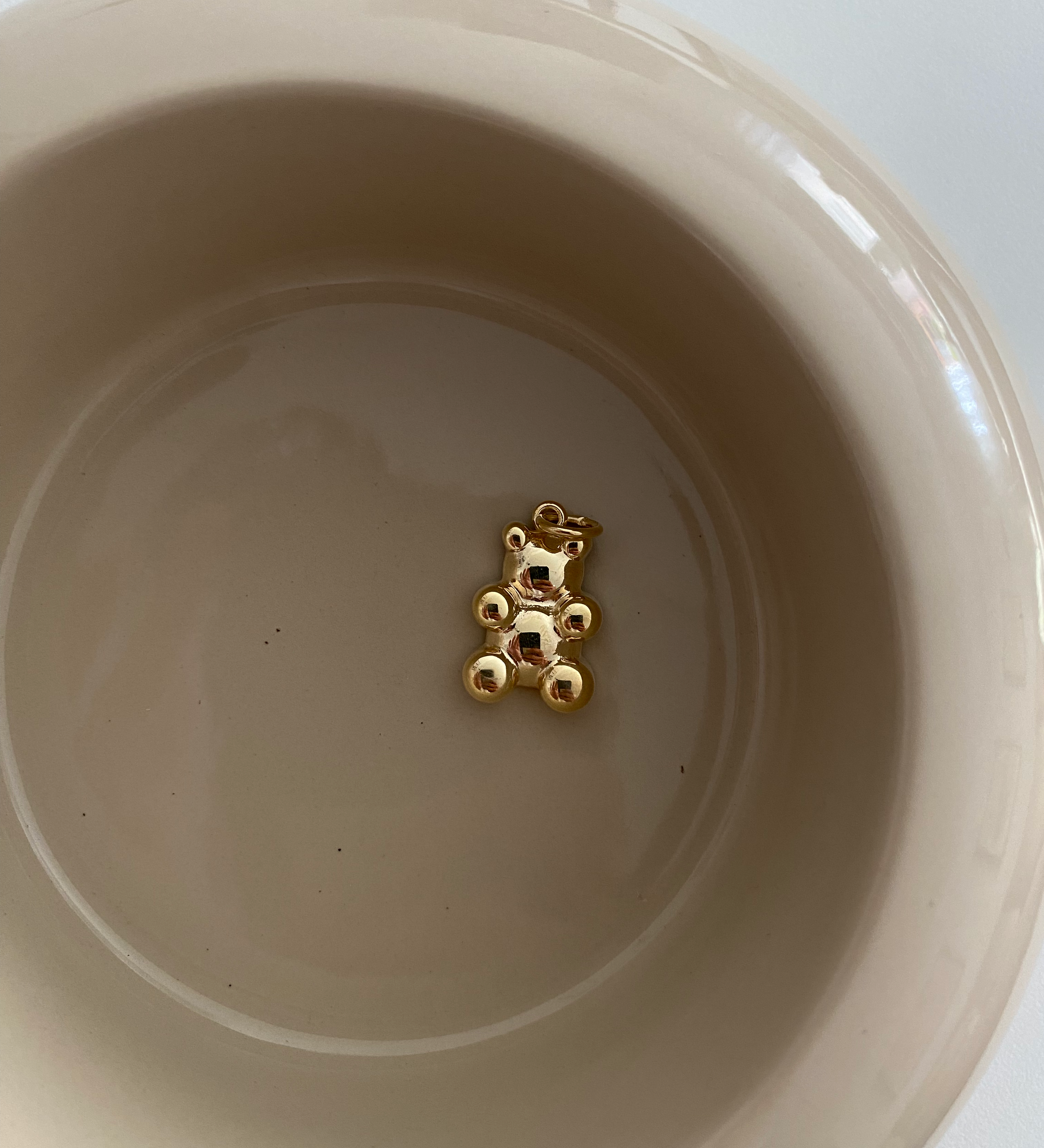 Clear Bear Anhänger Gold aus 925er Silber, liegend in beiger Keramikschale als minimalistisches Stillleben.