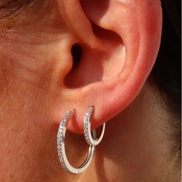 Detailansicht: Silberne Pavé-Creole ONE Line L am Ohr, kombiniert mit kleiner Creole.