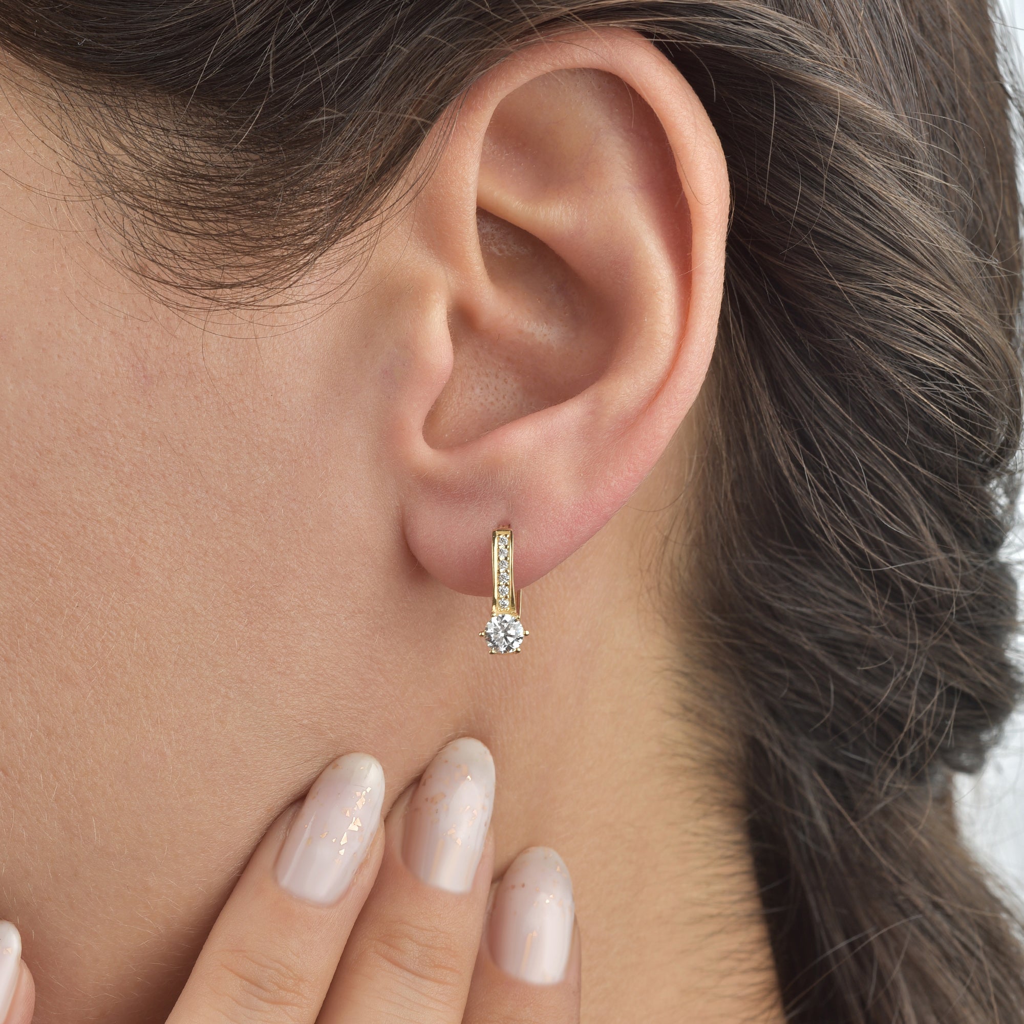 Close-up am Ohr: Creolen Shiny Solitaire Gold am Ohr getragen – funkelnder Solitaire-Zirkonia und Steinreihe, elegant und zart.