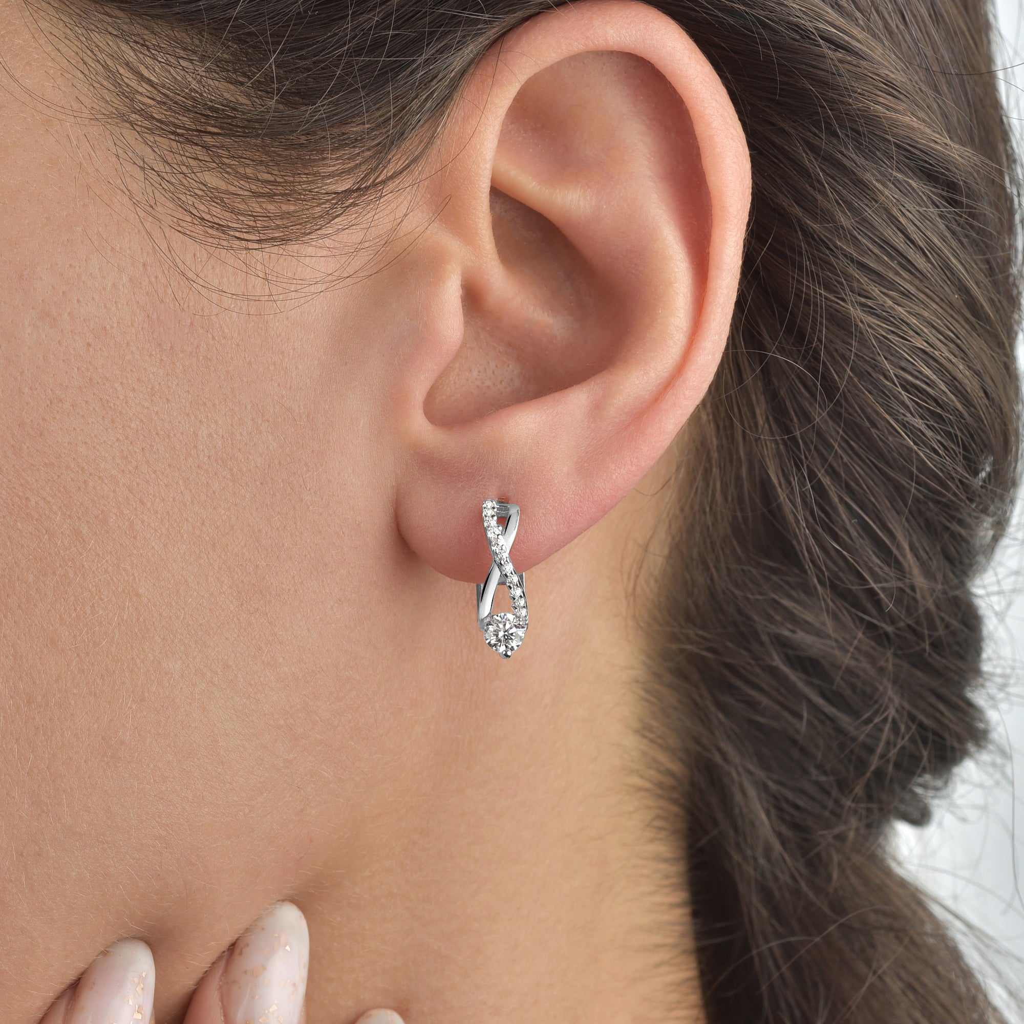 Silberne Creolen Unendlichkeit Solitaire mit Zirkonia als Ohrschmuck an einem Frauenohr.