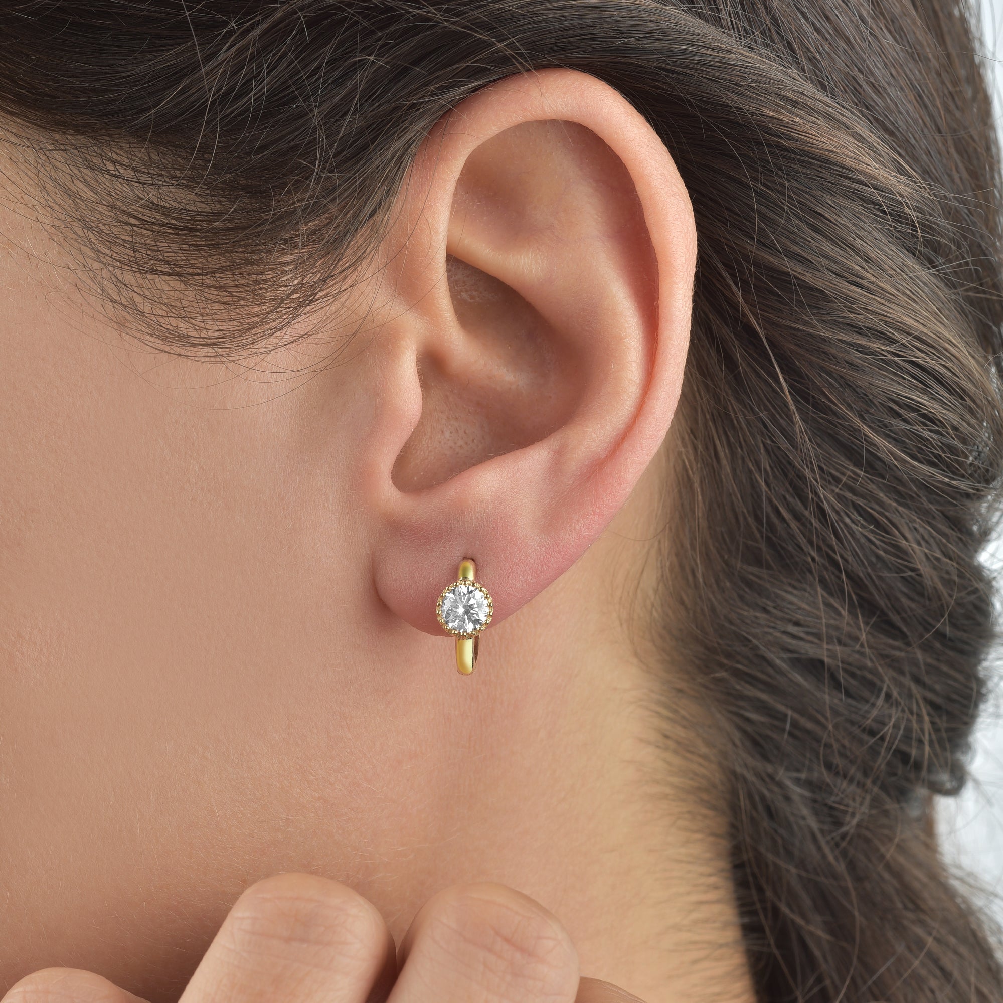 Goldene Mini-Creole mit weißem Zirkonia am Ohr getragen – dezenter Glanz und perfekte Alltagsgröße.