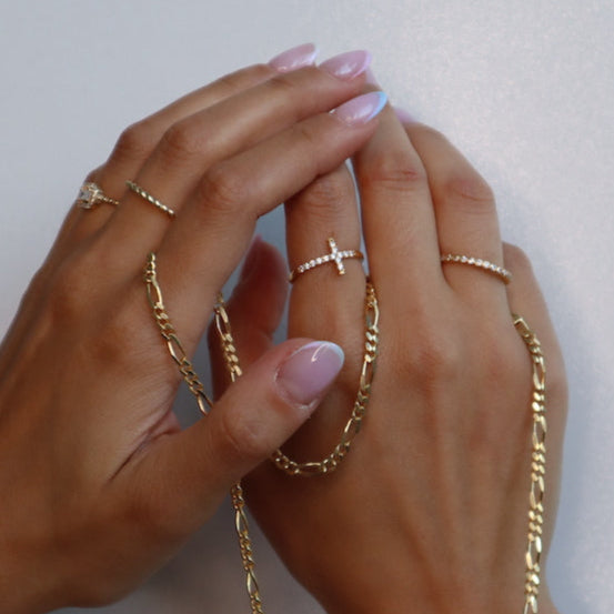 Zwei Hände mit Cross Ring und weiteren Goldringen und Kette, stylisches Ring-Stacking für Damen von Dkeniz.