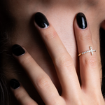 Nahaufnahme einer Hand mit Cross Ring in Gold und schwarzen Nägeln, eleganter Damenring von Dkeniz.