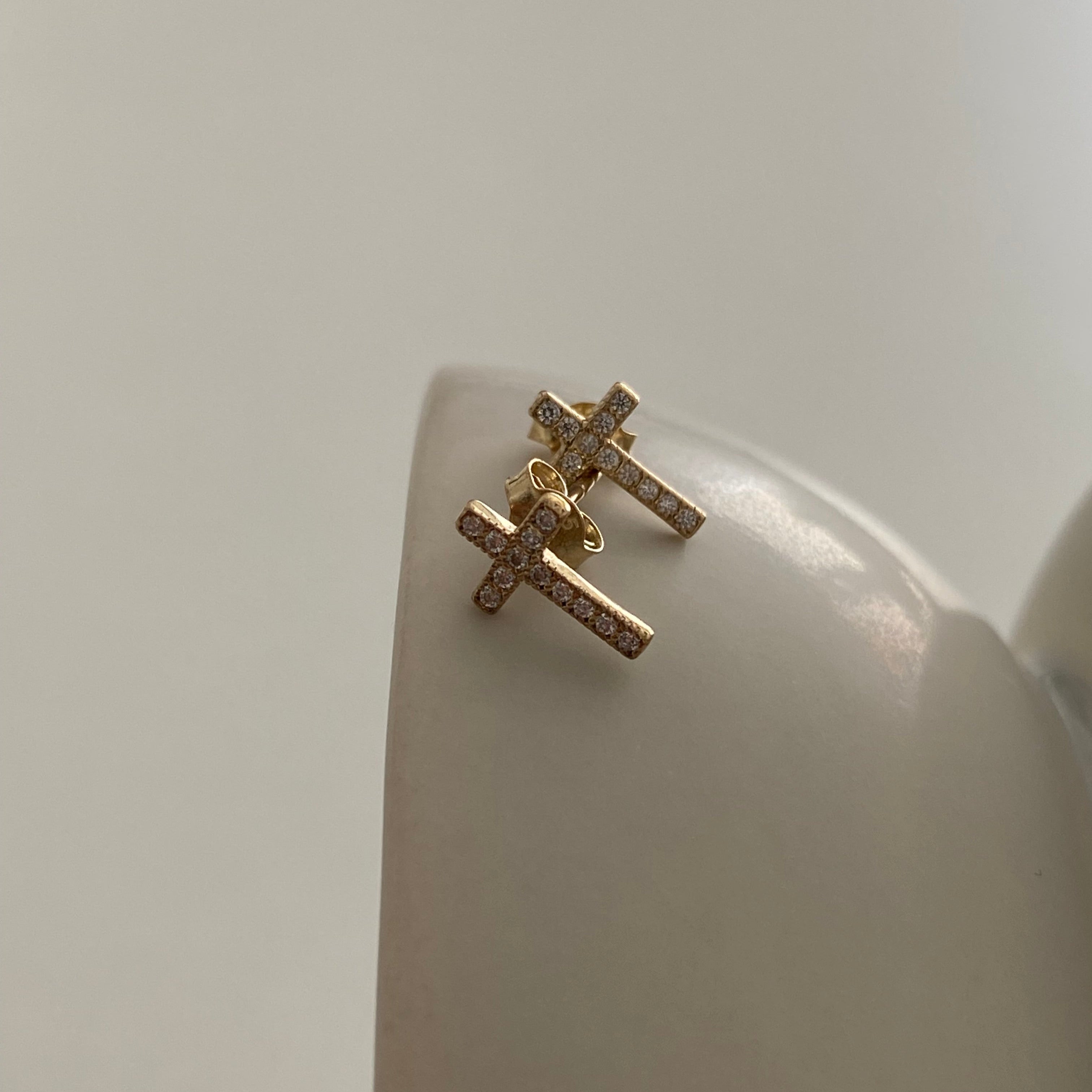 Zwei goldene Kreuz Ohrstecker mit Zirkonia auf Schmuckdisplay – Cross Zirconia Stud Gold.