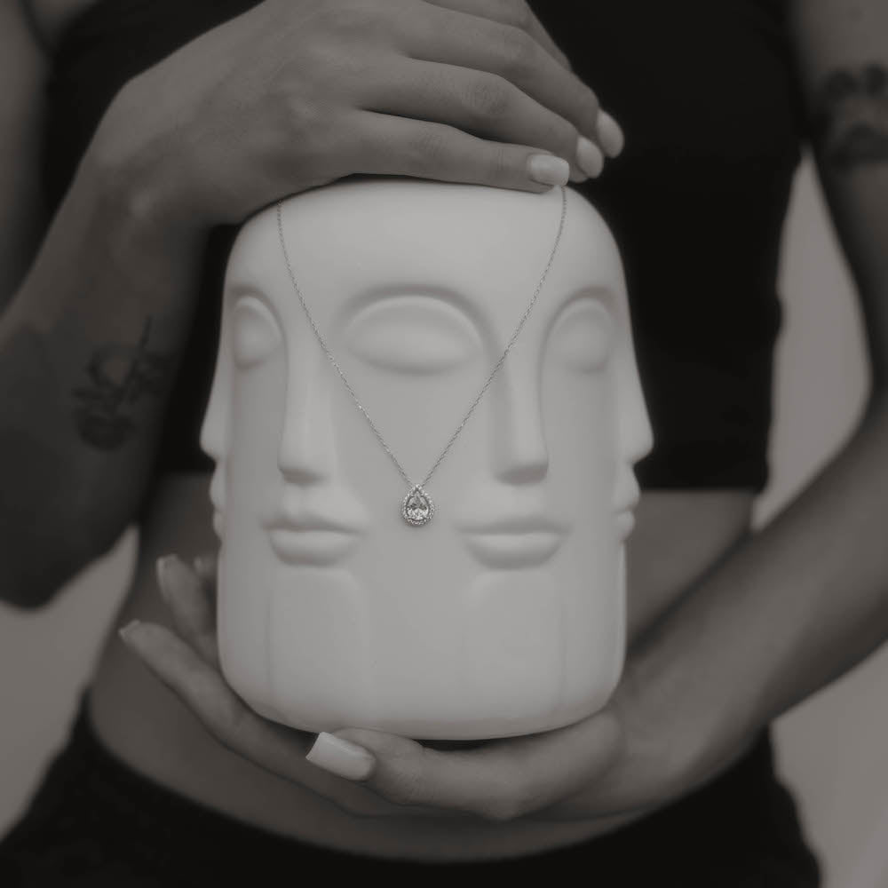 Silberne Drops Halskette mit Zirkonia an weißer Designvase.