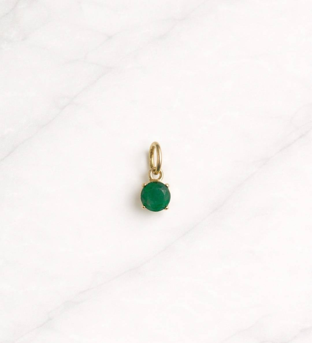 Emerald Bay Charm in Gold mit grünem Stein auf hellem Hintergrund.