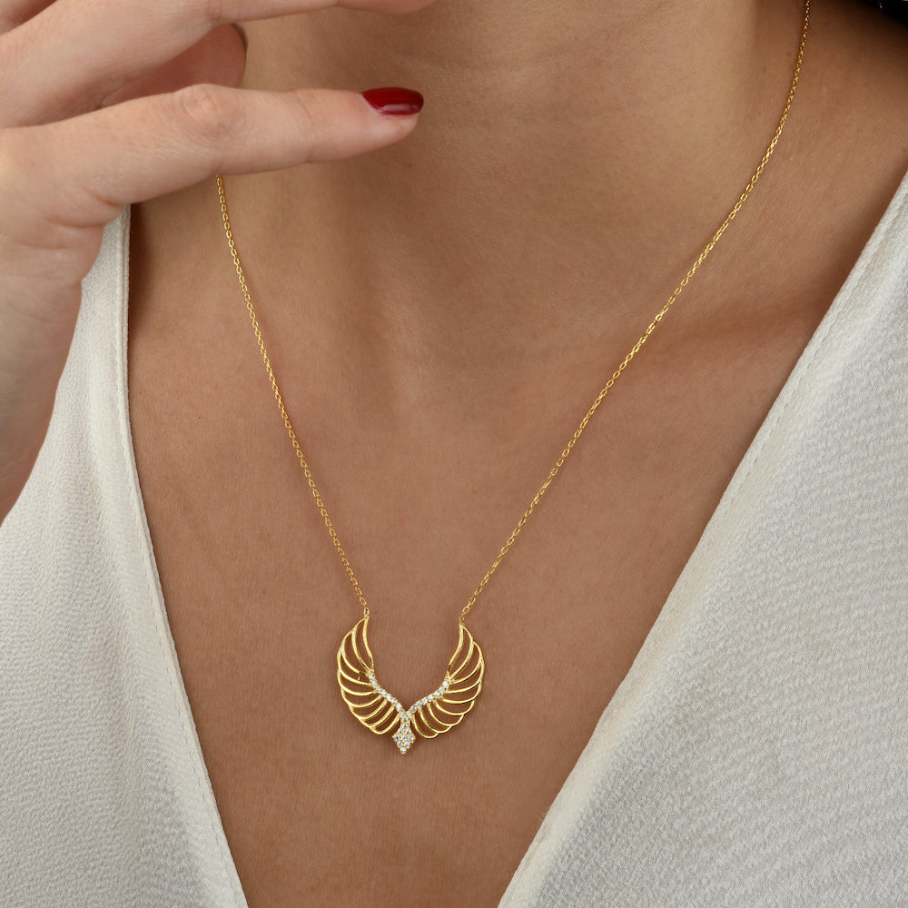 Angel Wings Halskette Gold getragen am Dekolleté – eleganter Engelsflügel Anhänger mit Zirkonia.
