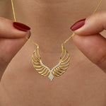 Close-up: Angel Wings Halskette Gold, filigrane Engelsflügel mit weißen Zirkonia in Händen gehalten.