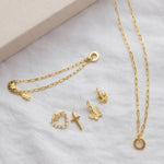 Goldfarbenes Ketten-Set mit Ring-Anhänger, dazu Charms: Herz mit Perlen, Kreuz, Schmetterling und Anker.