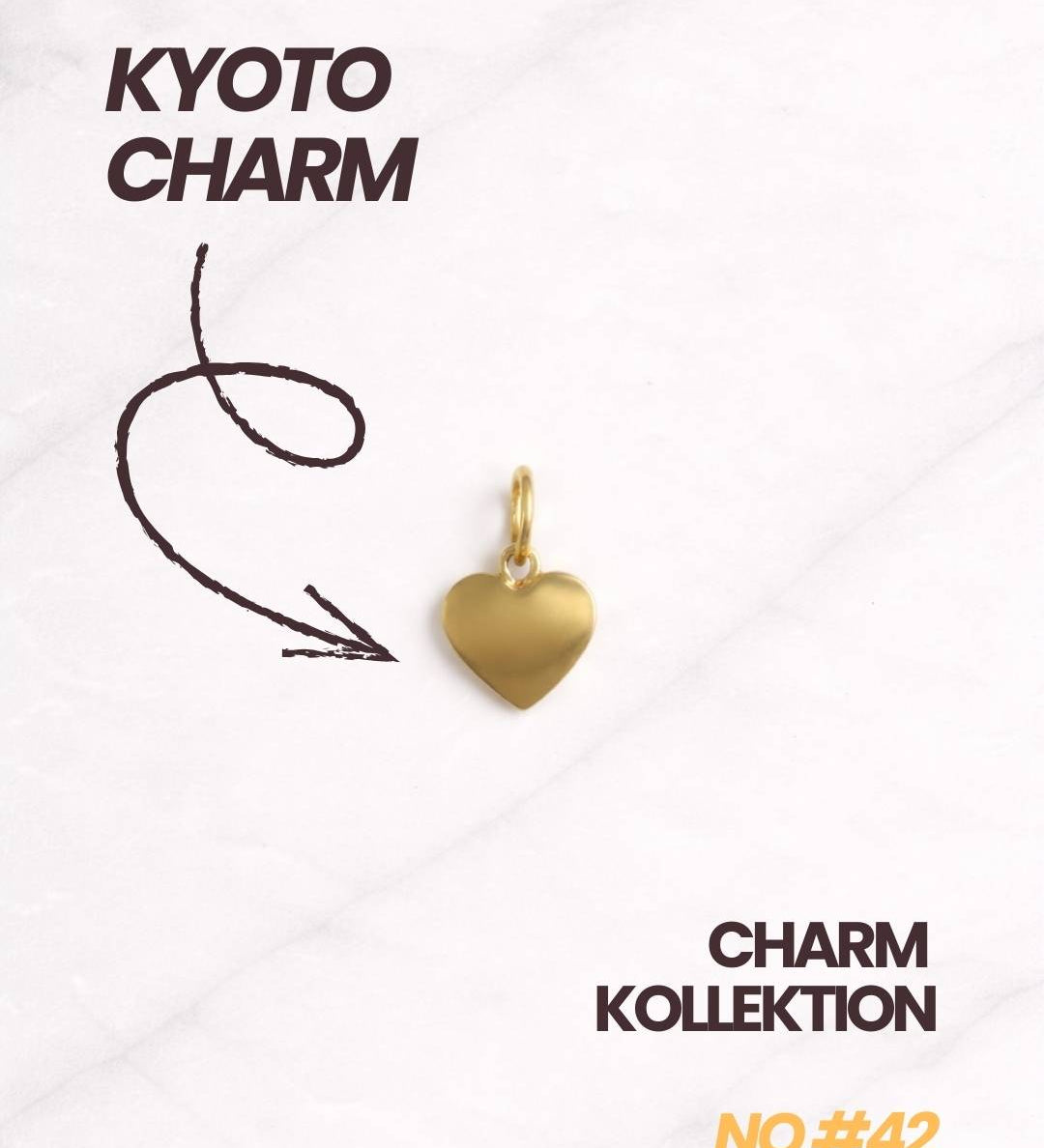 Kyoto CHARM Gold Herz Charm mit Kollektionstext auf hellem Marmorhintergrund.
