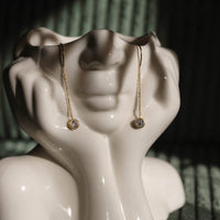 Goldene Edelstahl Ohrringe mit Zirkonia, hängendes Design, präsentiert auf weißer Gesichtsstatue, eleganter Schmuck für Frauen, DKENIZ