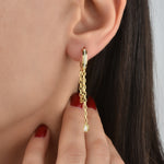 Hängecreolen Tropfen Gold am Ohr getragen – funkelnde Zirkonia und bewegliche Kette mit Tropfenanhänger.