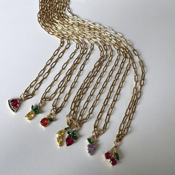 Goldene Halsketten mit Obst-Charms aus 925 Silber und Edelstahl, auf weißem Hintergrund arrangiert