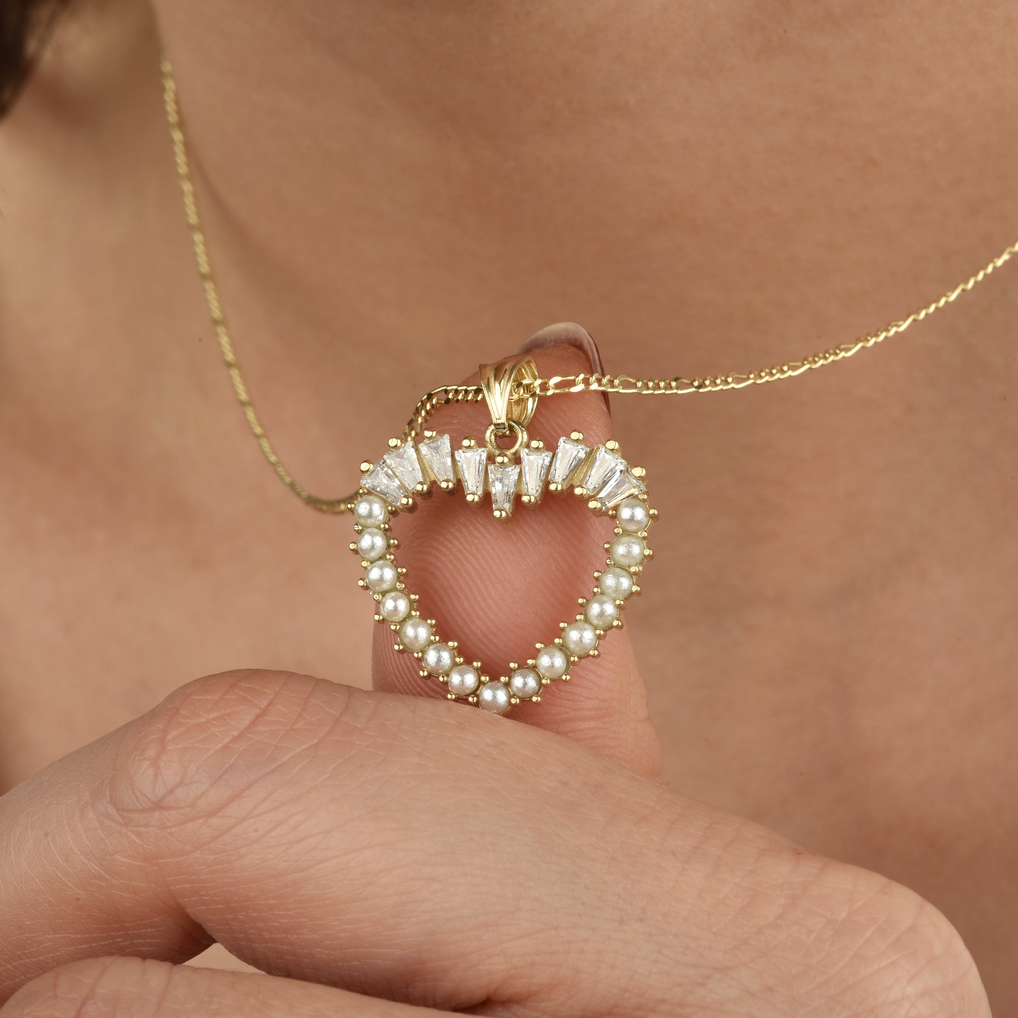 Detail: goldene Herz-Halskette mit Perlenrand und Baguette-Zirkonia, am Hals gehalten.
