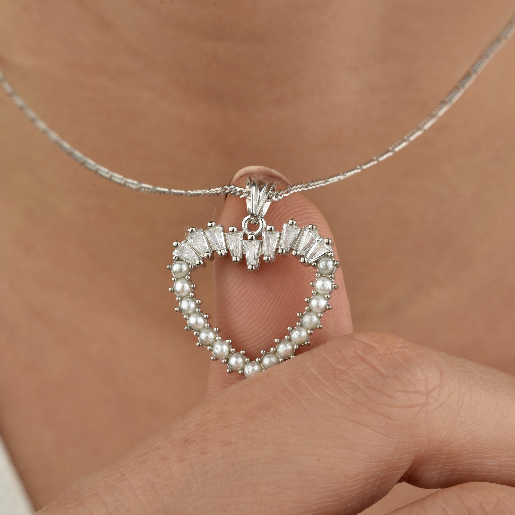 Detailaufnahme Herzanhänger: Perlenrand und weiße Baguette-Zirkonia in 925 Silber, rhodiniert.