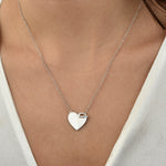 Silberne Herz Gravur Shiny Closure Halskette getragen am Dekolleté einer Frau.