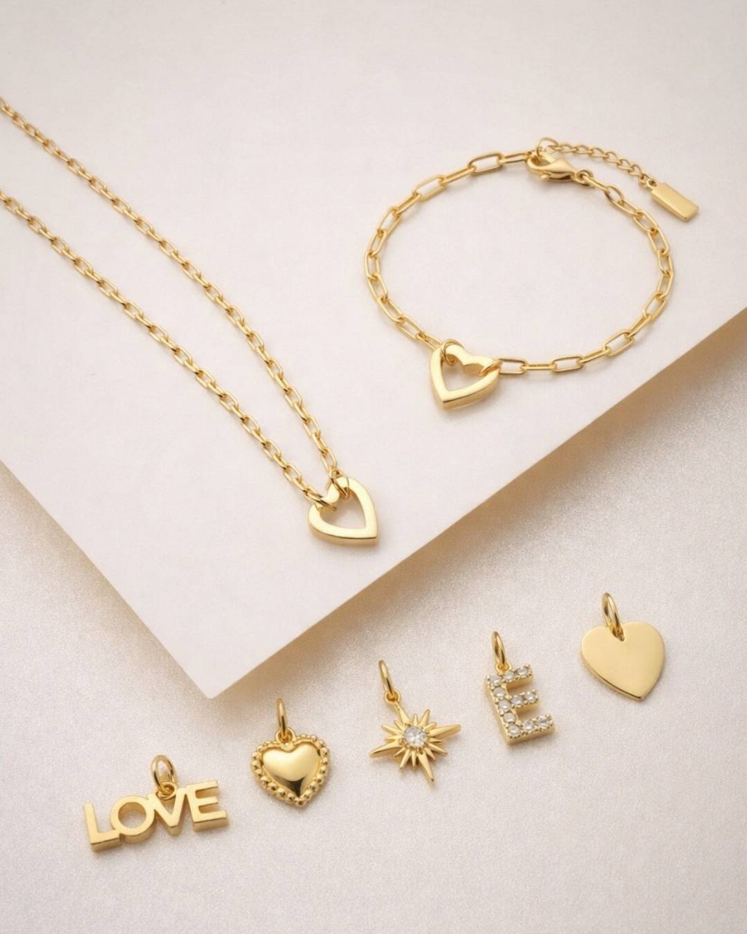 Goldfarbenes Schmuckset mit Herz-Kette, Herz-Armband und Charms: LOVE, Herz, Stern und Buchstabe E.