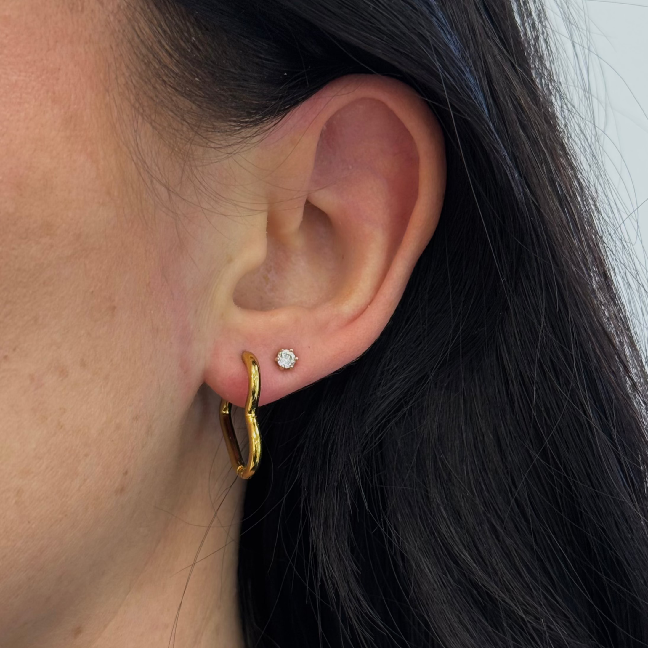 Goldene Herz Ohrringe getragen am Ohr – stilvoller Damenschmuck