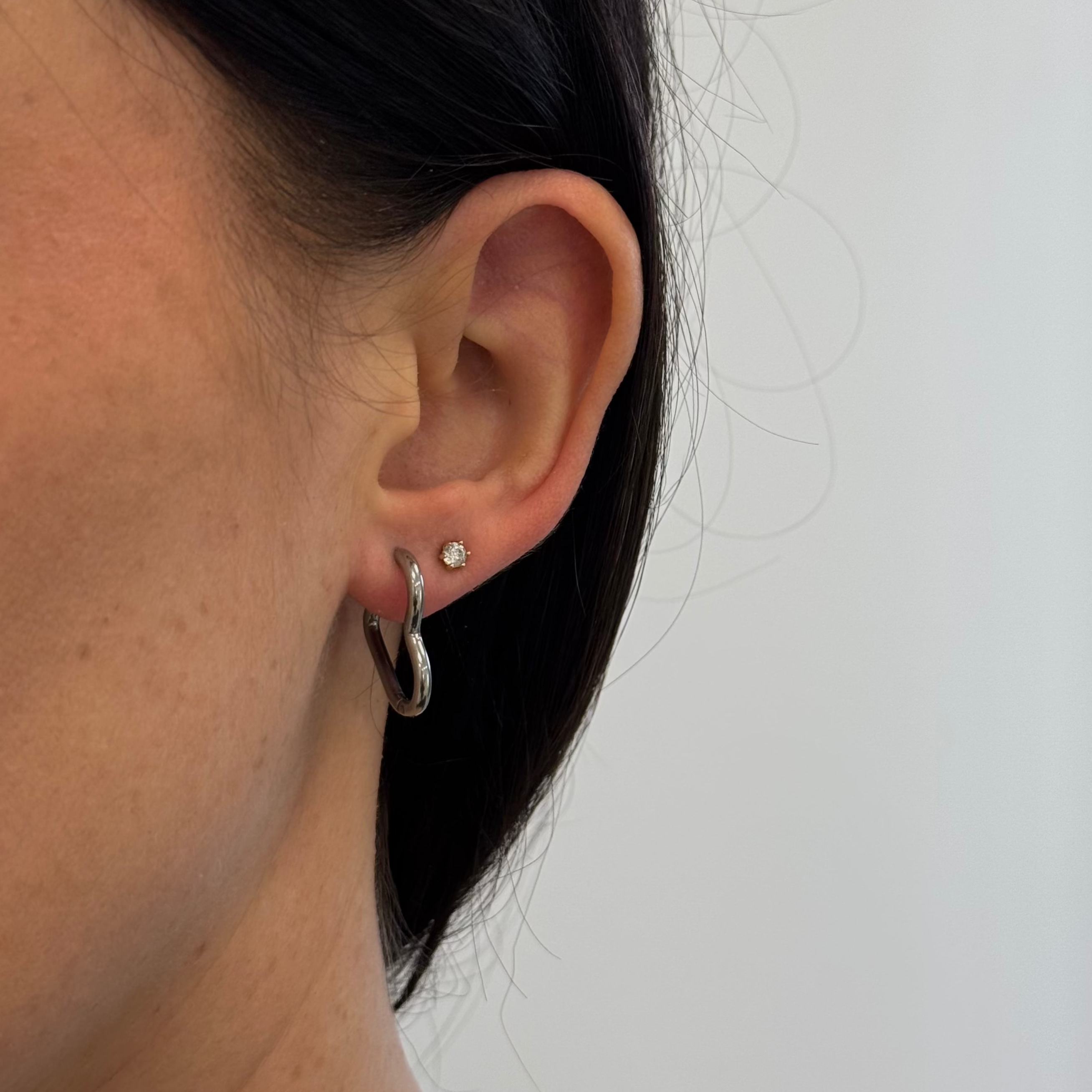 Silberne Herz Ohrringe getragen am Ohr – moderner Damenschmuck