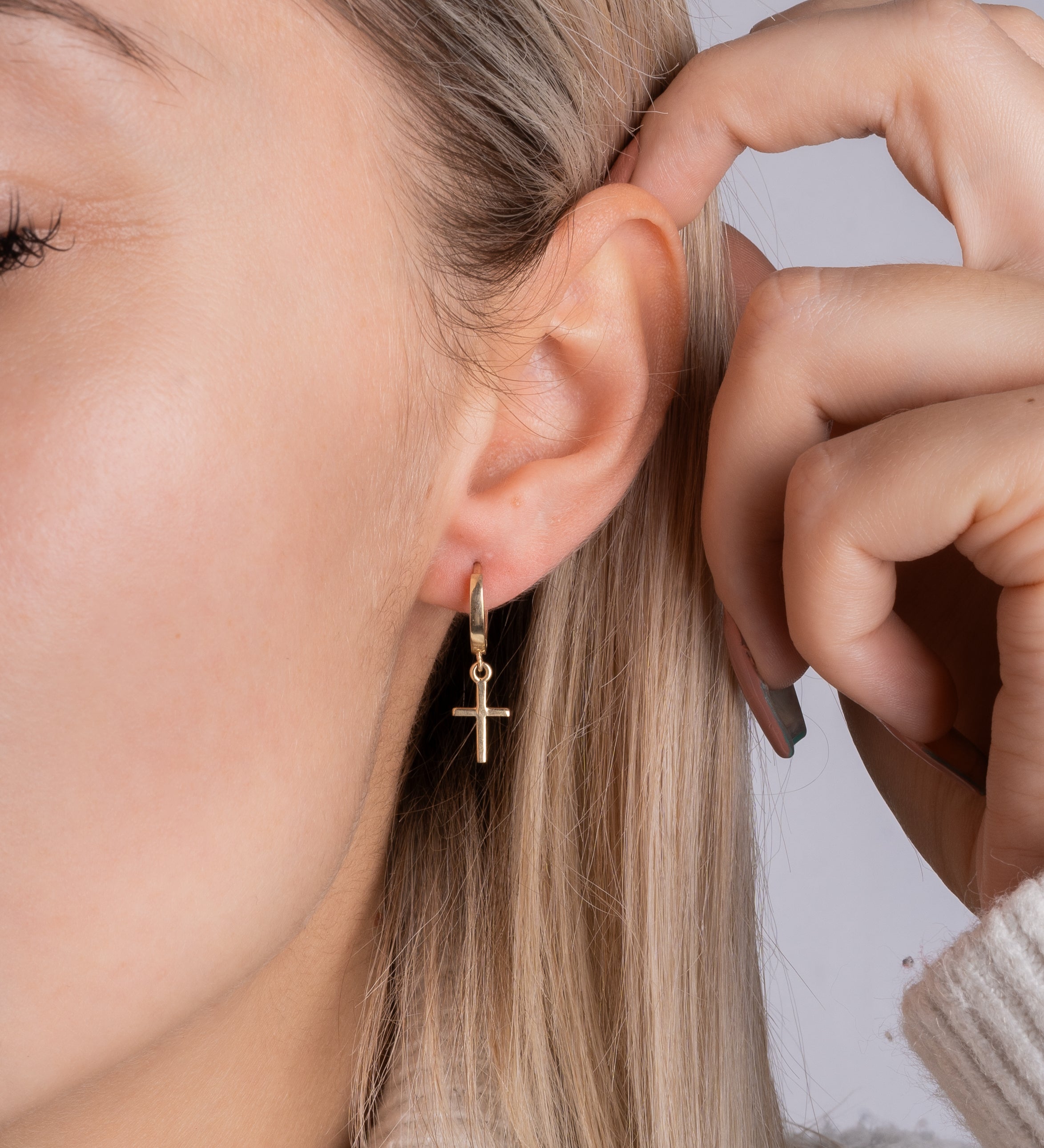 Tragebild: High Polished Cross Hugy Gold Kreuz-Huggies am Ohr – minimalistisch, elegant, wasserfest.