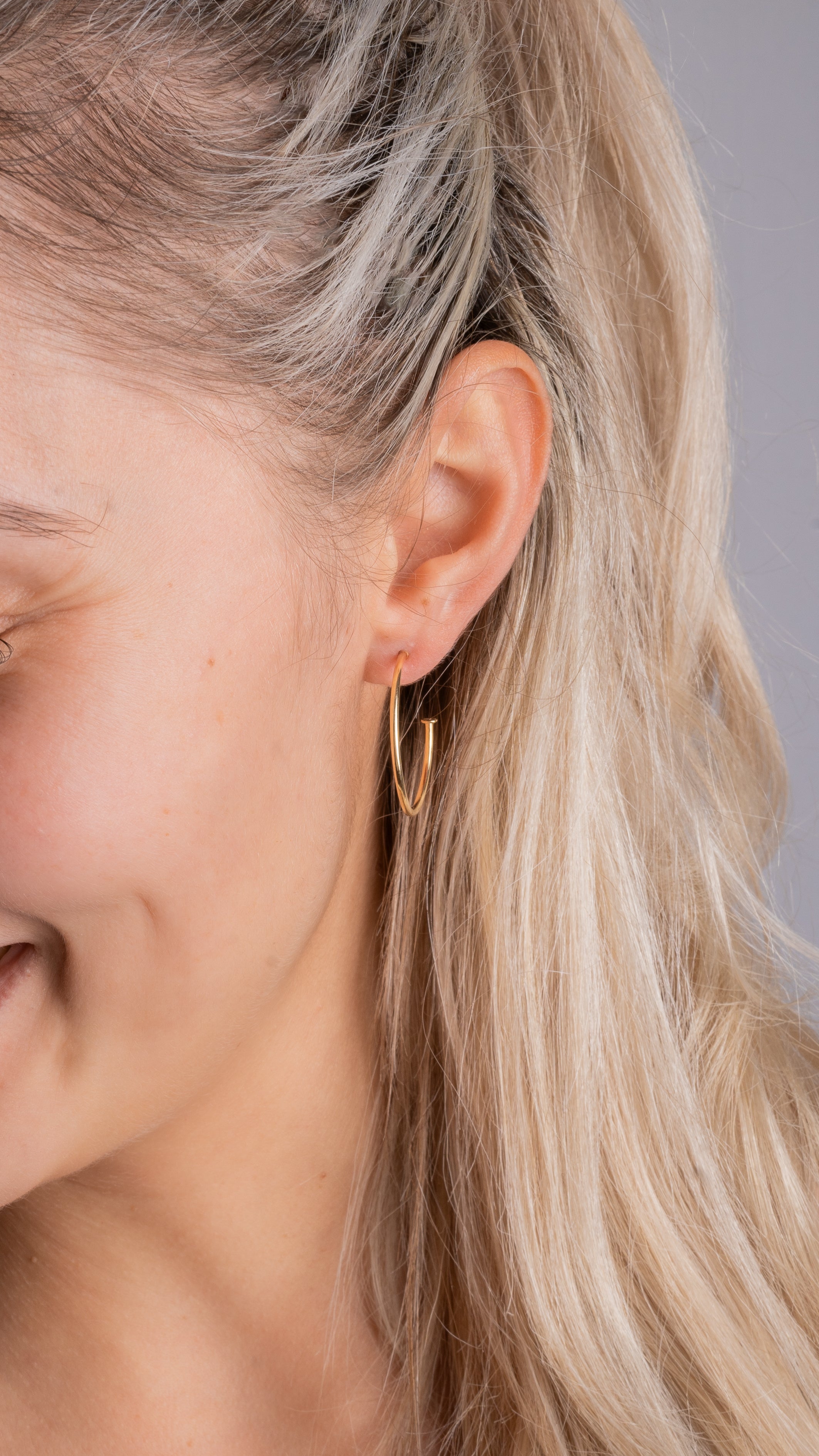 Model trägt Classic Thin M Creolen in Gold – elegante, dünne Hoop Earrings im Alltag.